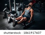 Muscular man using weights machine for legs at the gym. Hard training