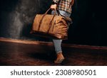 Small photo of Man Holding His Canvas Travel Bag. Medium shot of an athletic man with his dark brown canvas duffle bag
