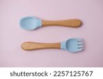 A set of colored silicone forks and spoons with a wooden handle. Baby feeding and nutrition concept. Top view, flat lay.