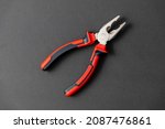 Pliers in red and black colored on a black background with blank text space