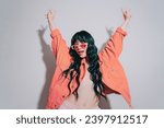 Small photo of Cheeky emotional fashion young woman with long green color hair and trendy peach color lips, jacket and sunglasses dances on white background. Playful Hipster woman having fun. Color of the 2024 year.