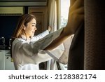 Overjoyed young beautiful woman standing by bedroom and opening curtains look in window distance meet welcome new day. Smiling female feel excited about life career opportunities or perspectives.