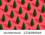 Minimal composition pattern background of green Christmas trees on pastel red. New Year concept.