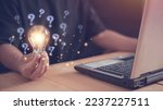 Small photo of Businessman using laptop computer and holding light bulb with question mark icon, New ideas and innovations arise and search for answers. Critical thinking and analysis concept.