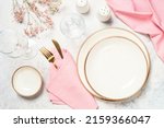 Table setting with plate, flowers and cutlery at white kitchen table. Spring or summer table setting. Top view with copy space.