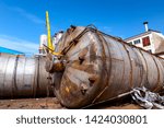 Small photo of Obsolete massive old metal silos, tanks are lain down on the ground, waiting cassation for recycling metal.