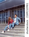 Small photo of Pretty couple sitting on the stairs while looking at eachother