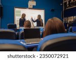 Female university student picked by the professor writing answers on smart board during classes at school.