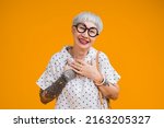 Portrait of attractive funky asian tattoo cheerful grey-haired elder old senior woman touching her chest isolated over yellow pastel background color,surprise and over exited feeling expression