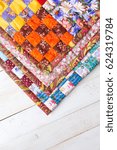 Small photo of Part of symmetric geometry pattern color patchwork quilt on a white wooden background. Scrappy blanket with pattern of small squares. Handmade. Top view. Concept of handmade.